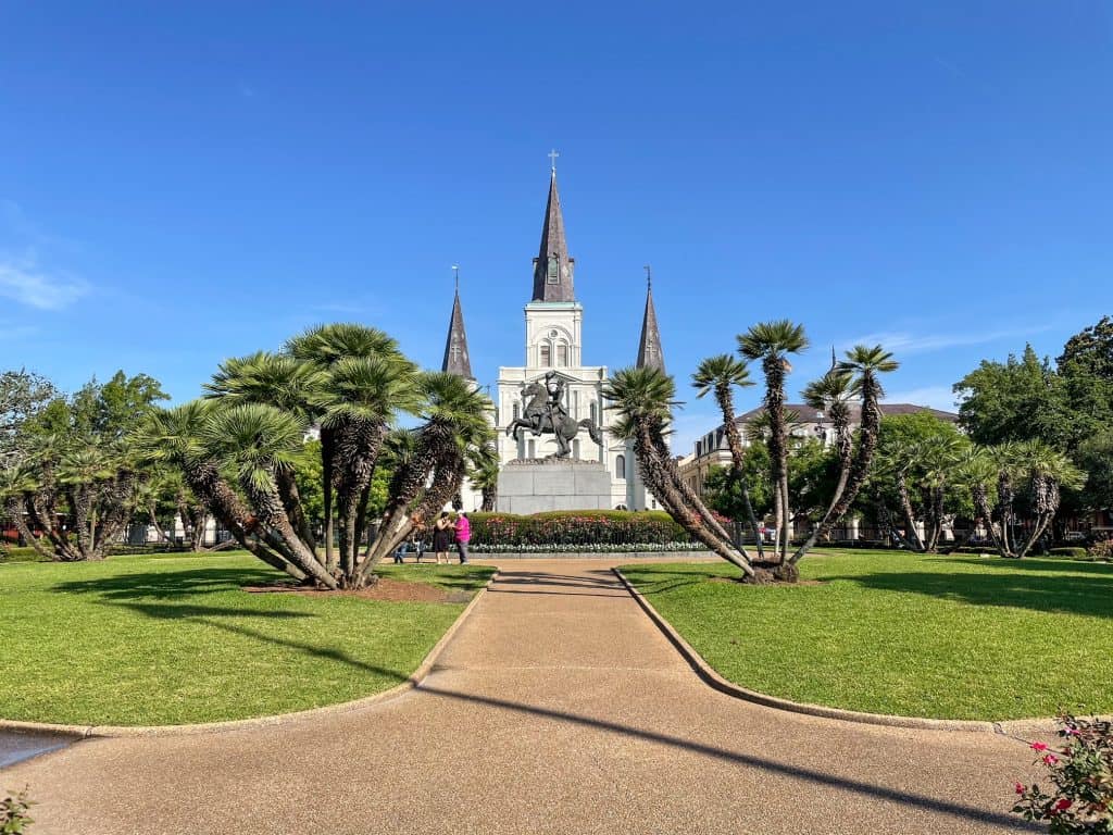 Entering Jackson Square with trees, a statue, a fountain and church in the background.