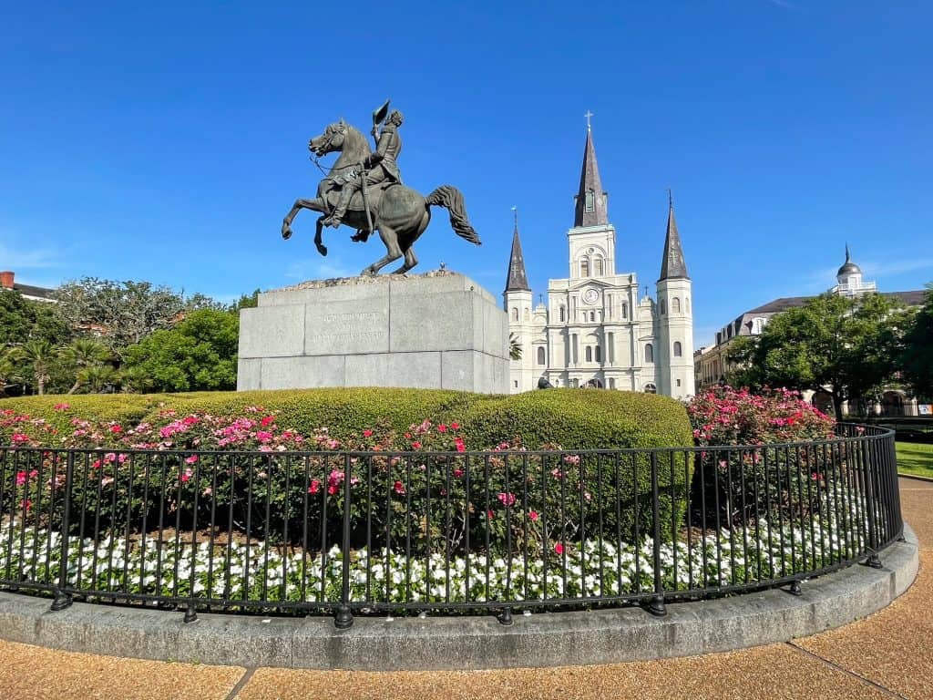 Statue of Andrew Jackson surrounded by bushes and flowers in the middle of Jackson Square, New Orleans.