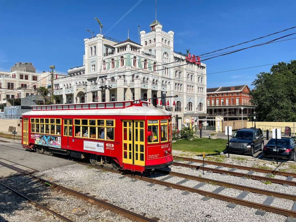 A red streetcar passing in front of the JAX building near the riverfront in the French Quarter.