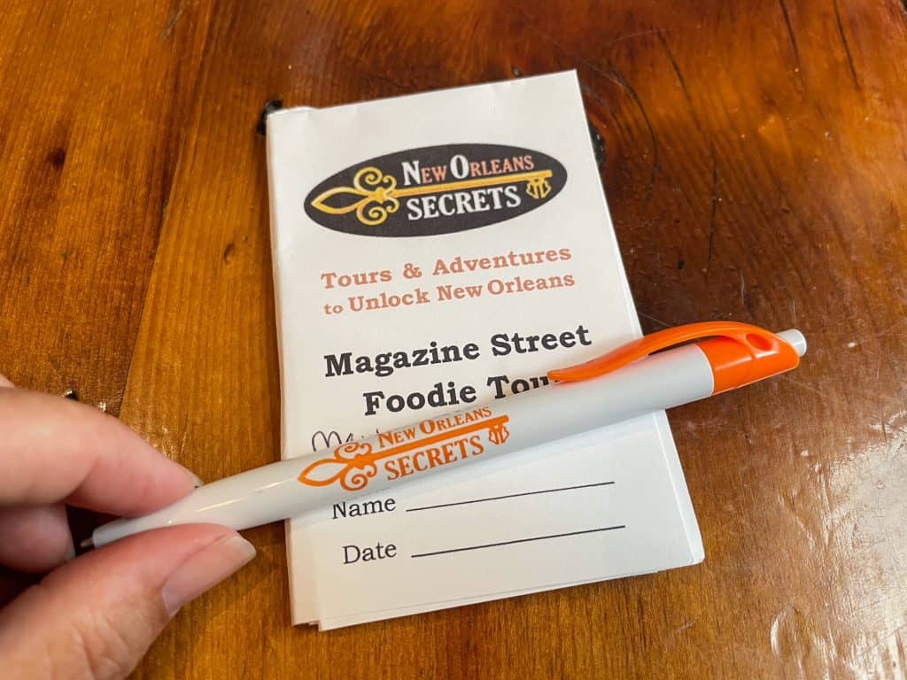A pen and small notepad that have the New Orleans Secrets logo for the food tour.