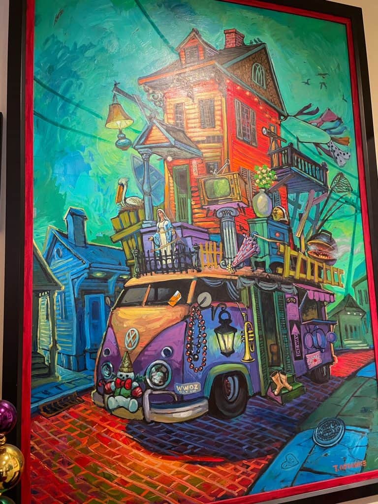 A vibrant painting by artist Terrance Osborne of a VW bus with a New Orleans style house on top.