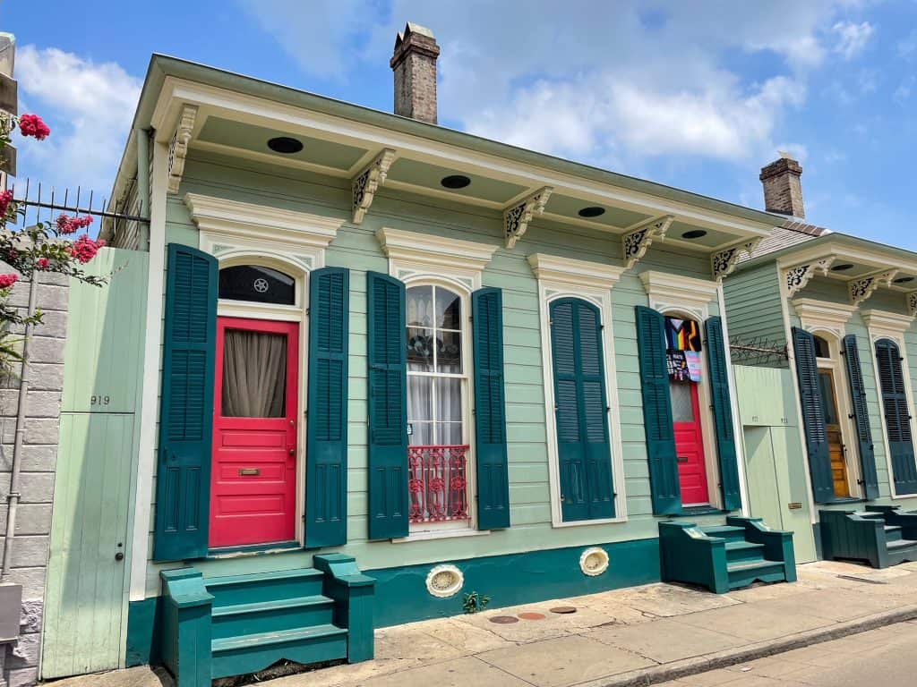 An adorable lime green house with pink doors, and dark green shutters in New Orleans.
