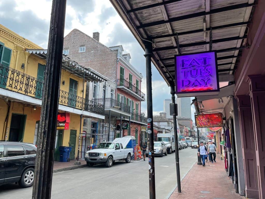 Walking down a street in the French Quarter with a sign that says "Fat Tuesday".