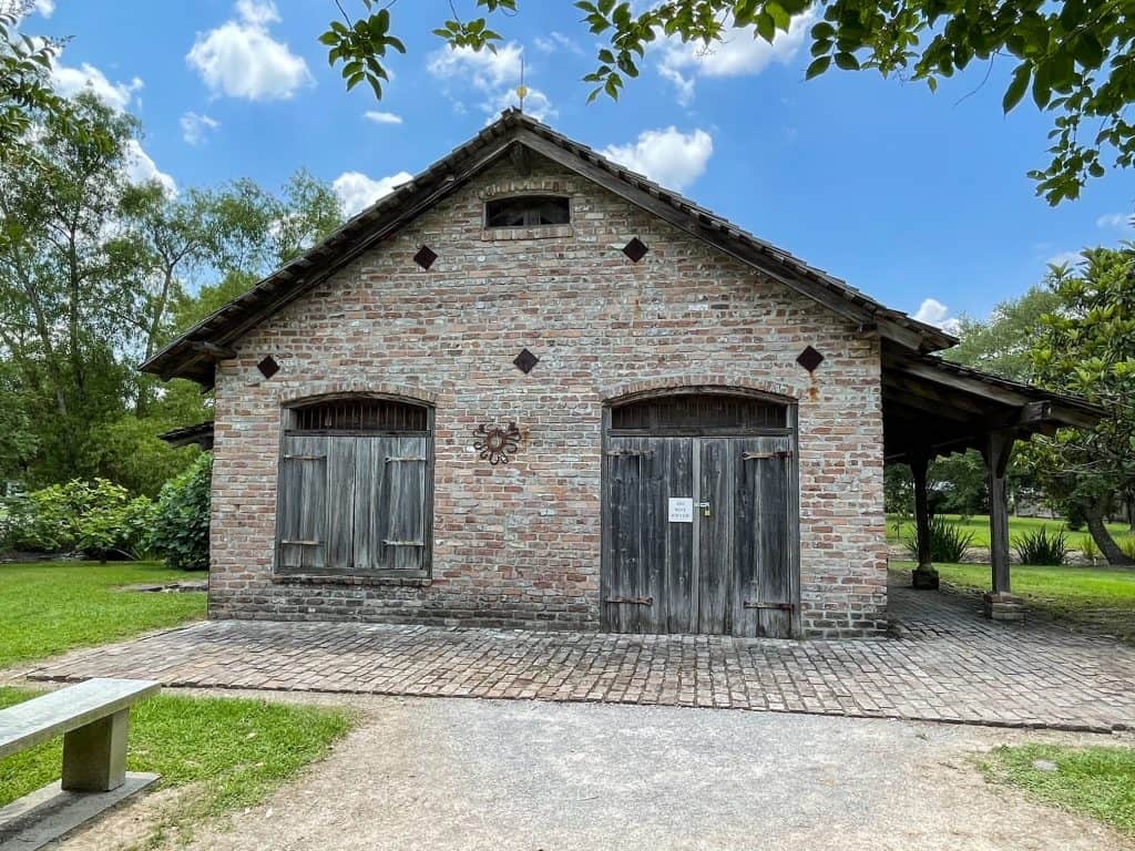 An old brick building with wooden doors on a plantation.
