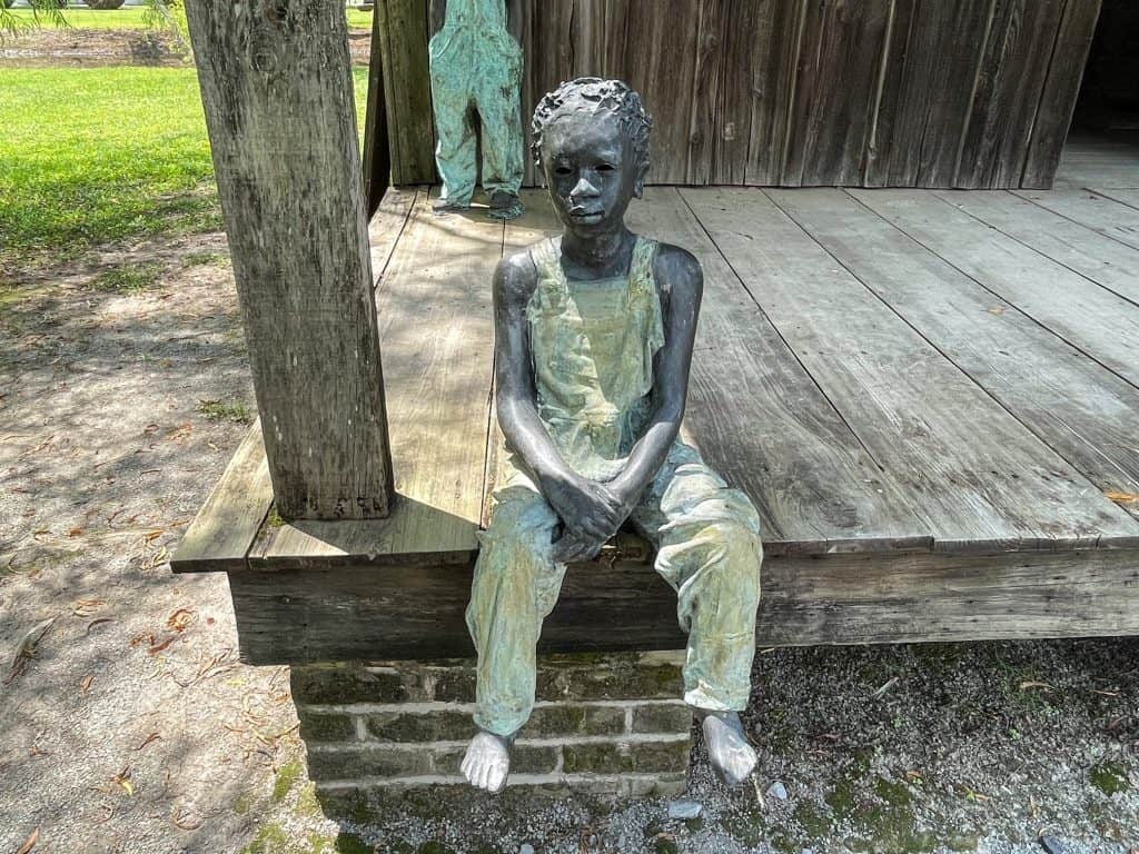 A close up of a slave child statue with a solemn and sad expression.