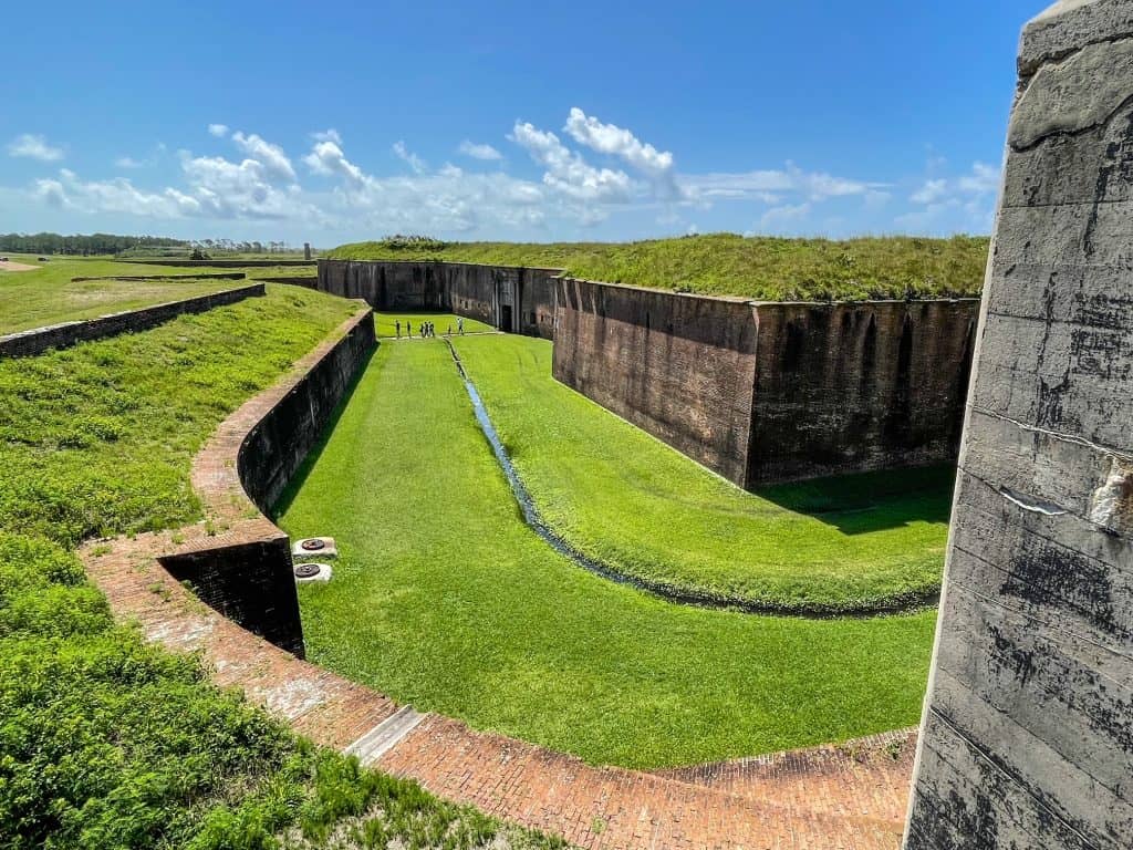 View of the outer brick walls of Fort Morgan and green grass surrounding it in Alabama.