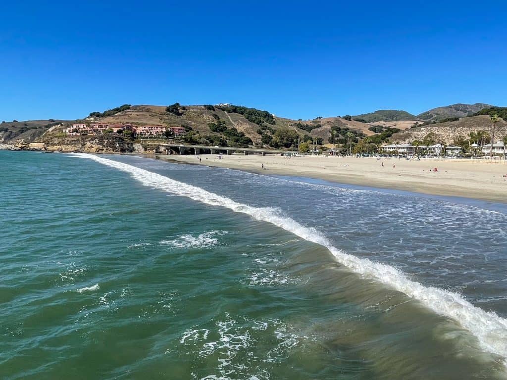 Looking at the Pacific Ocean, shoreline and beach at Avila Beach with turquoise green water.