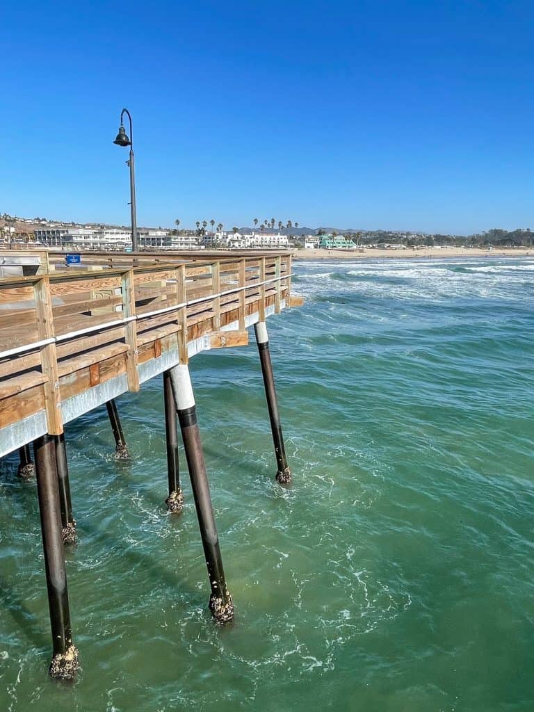View of Pismo Beach Pier, the aqua green Pacific Ocean and beach in the distance.
