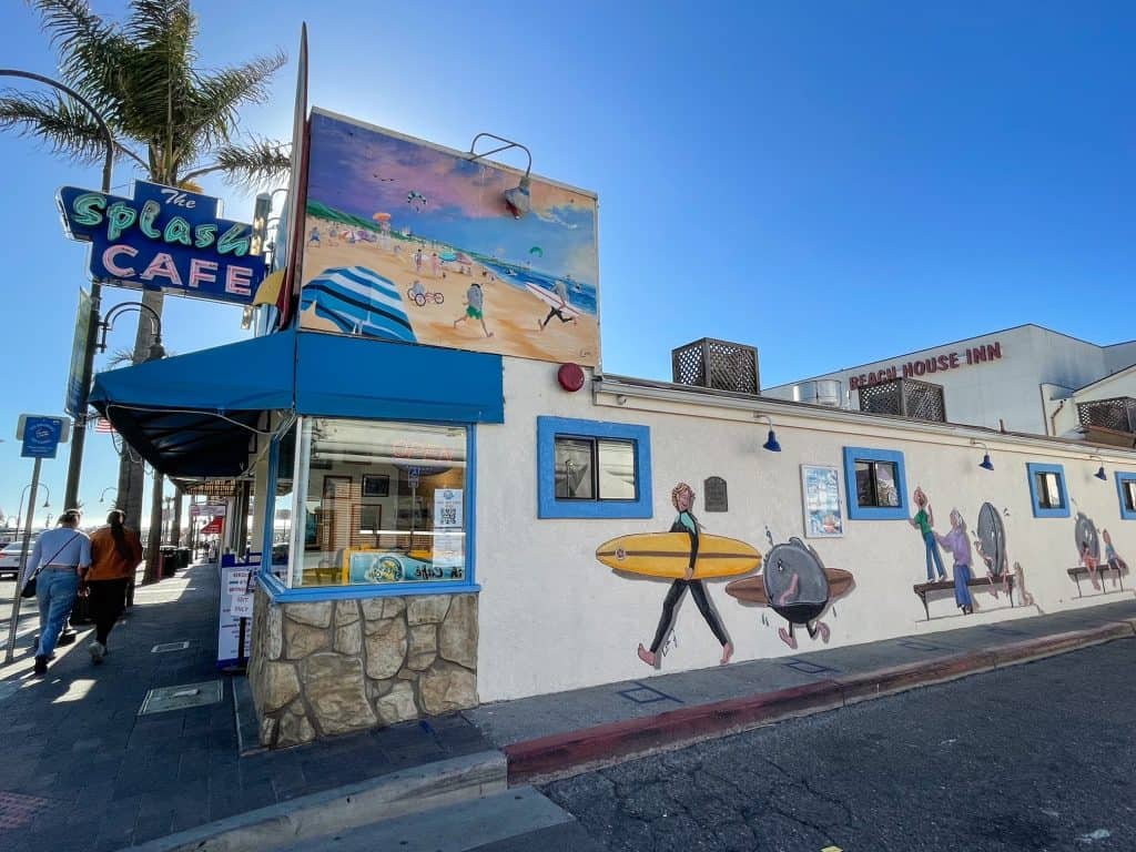The front of Splash Cafe with colorful and fun clam characters with people painted along the wall in Pismo Beach.