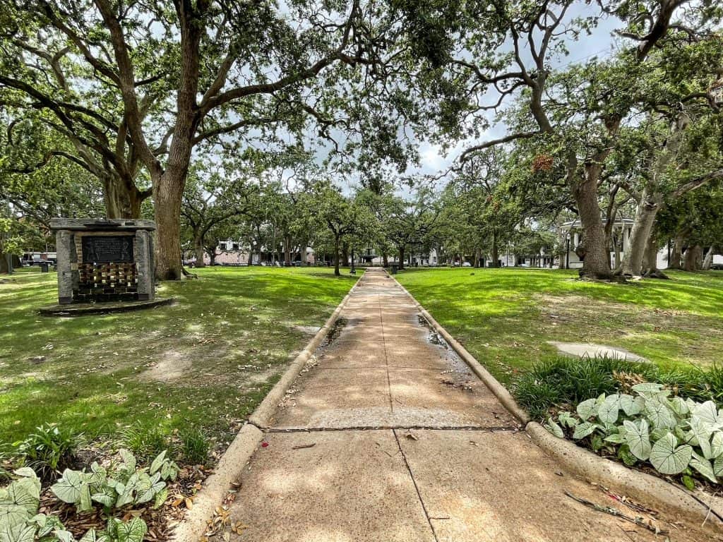 Walking in Bienville Square with trees, a fountain and grass in Mobile, Alabama.