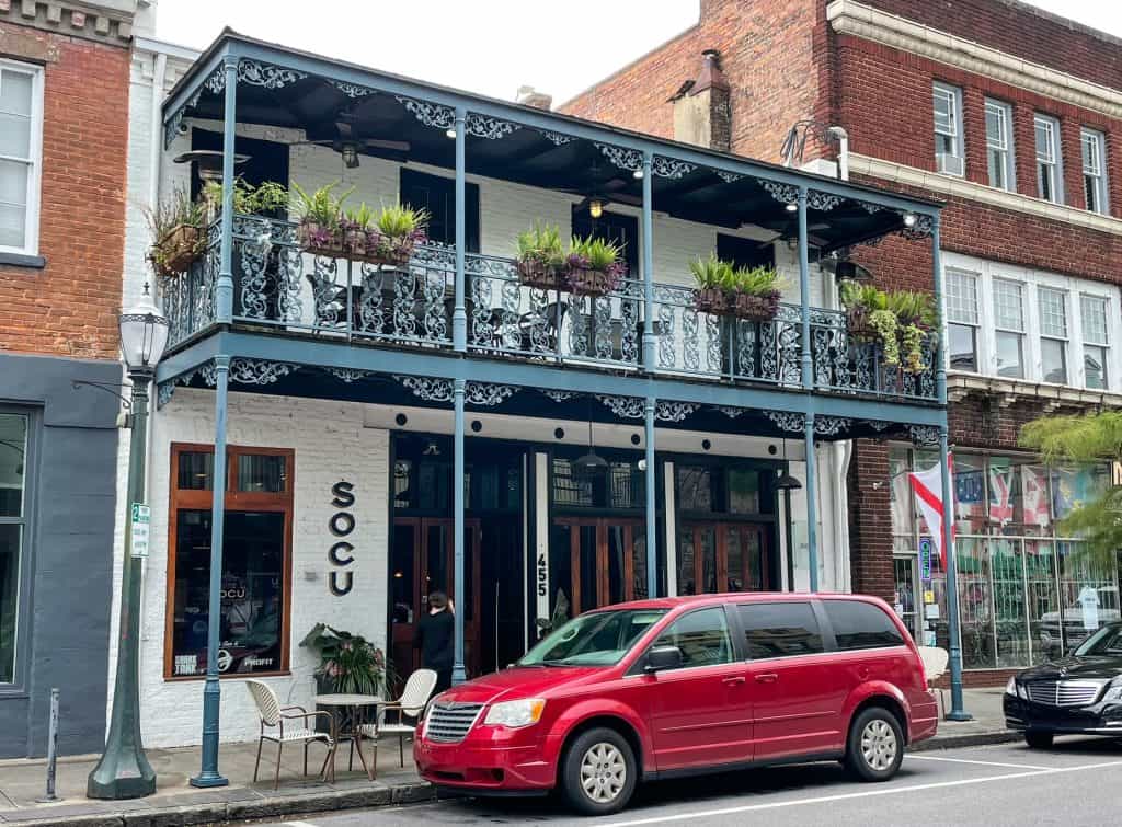 A charming two story historic building in downtown Mobile resembling a style from New Orleans with wrought iron balcony.