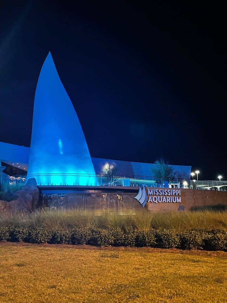 The sail at the entrance to the aquarium lit up in blue at night.