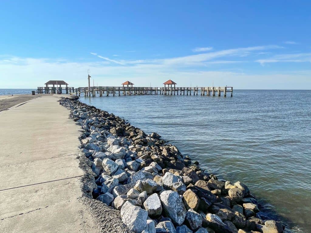 Looking out at the curving Moses Pier with three covered huts in Gulfport.