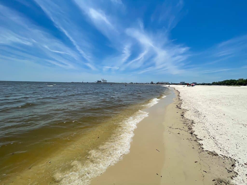 Standing in the shoreline as the water splashes my feet looking down the length of the beautiful beach.