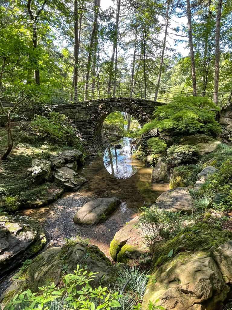 The arch of the Bridge of the Full Moon creates a half moon reflection in the water in the creek below.