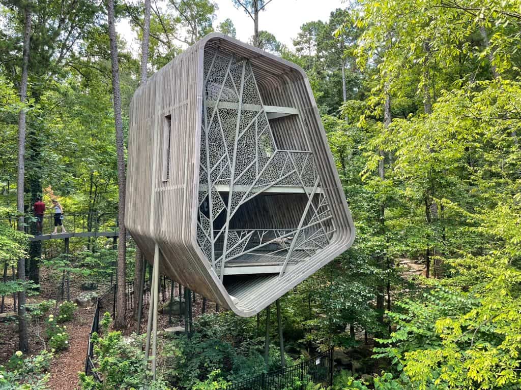 Standing on elevated walkway directly across from the Evans Tree House admiring its beauty and intricate architecture style and surrounded by trees at Garvan Woodland Gardens in Hot Springs, Arkansas.