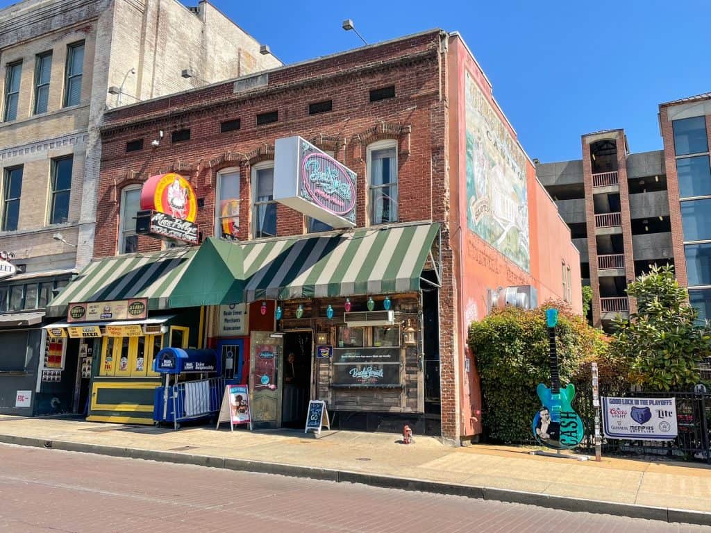 A vintage building with awnings on Beale Street and a large colorful guitar next to it.