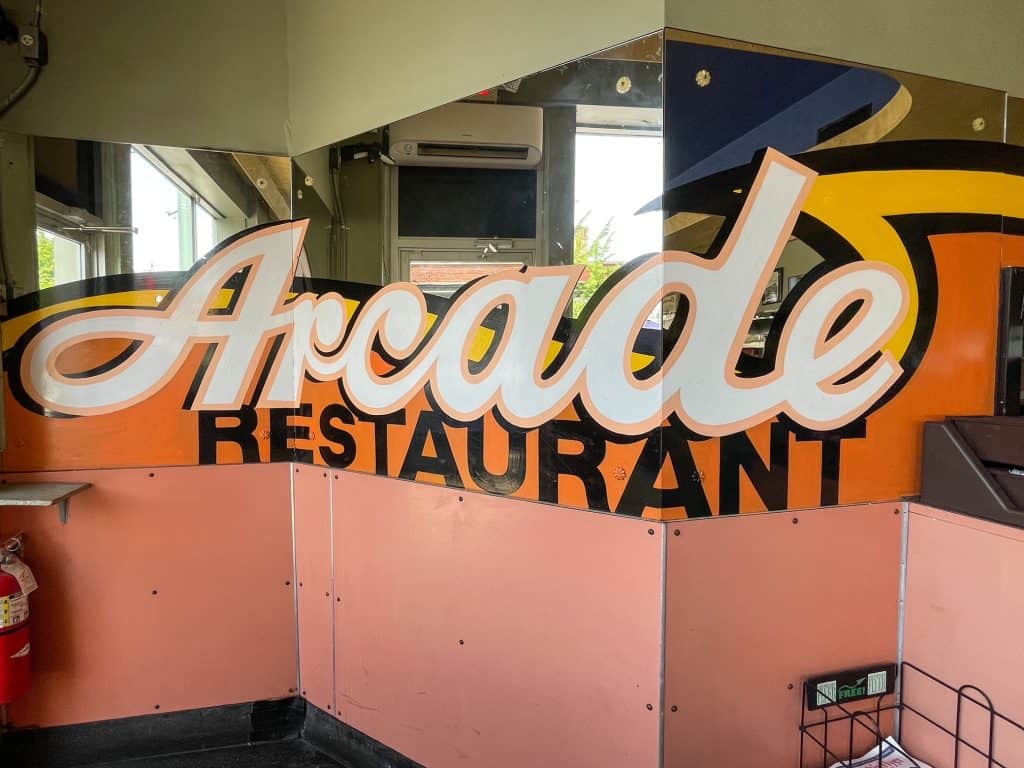 A big logo sign for the Arcade Restaurant in pink, orange, and black colors.