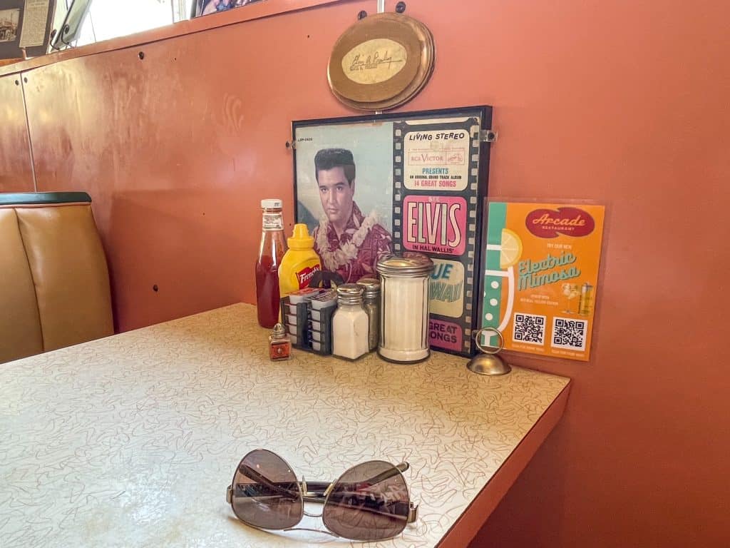 Sitting in the pink colored booth that Elvis Presley always sat in at the Arcade with a photo and plaque noting it.