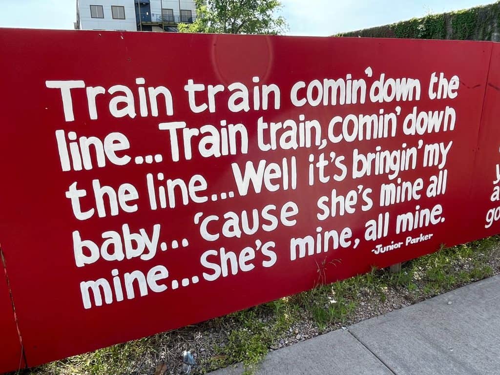 A painted quote about taking the train painted on a board along Main Street.