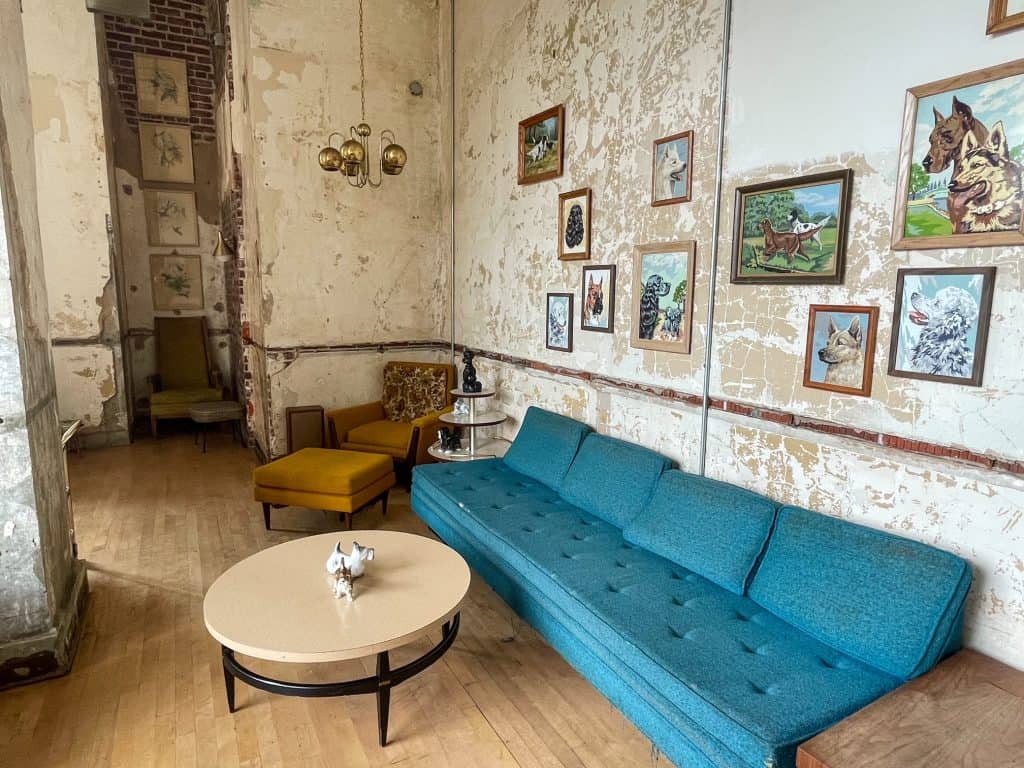 A cozy blue couch, table and chair with a vintage feel in a secret bar within Crosstown Concourse in Memphis.