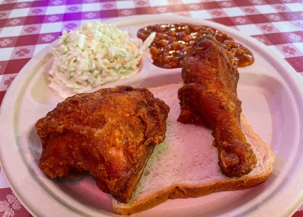Two pieces of fried chicken on a piece of bread with baked beans and slaw at Gus's Fried Chicken in Memphis.