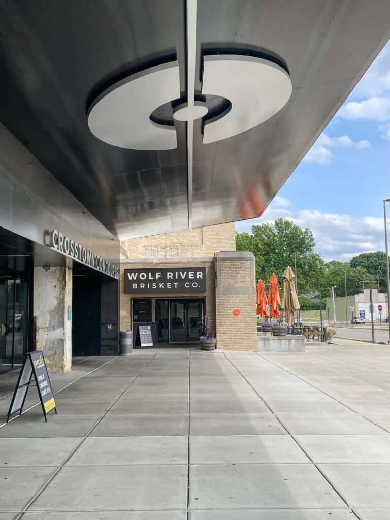 Wolf River Brisket restaurant with an entrance at the front of the Crosstown Concourse building and a the logo to the building above on the entrance covering.