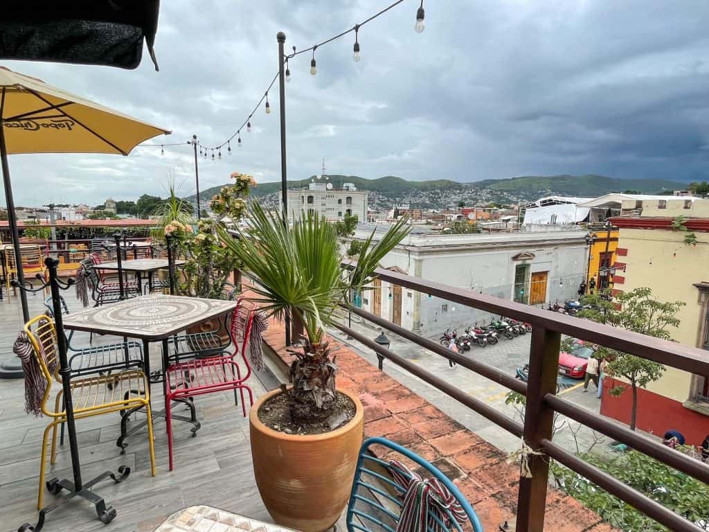 Sitting at a table of a rooftop bar with views of the city and surrounding green mountains of Oaxaca.