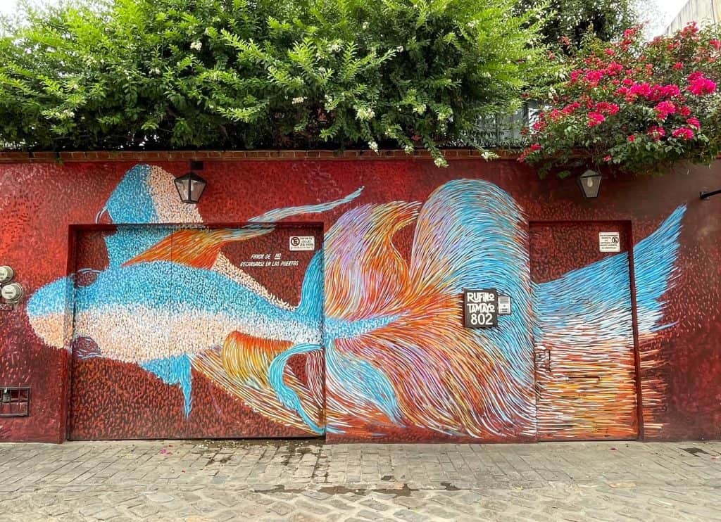 An art mural that is colorful blue, white, and orange fish against a red background.
