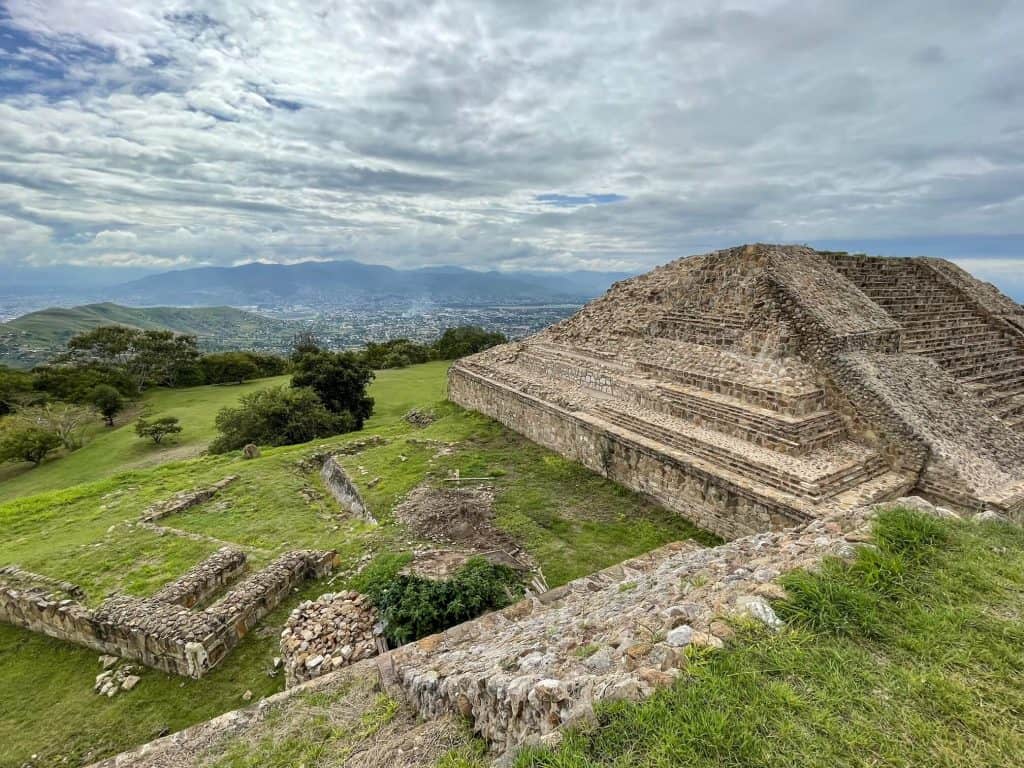 A beautiful stone pyramid while looking out at the valley beyond with greenery all around at Monte Alban.