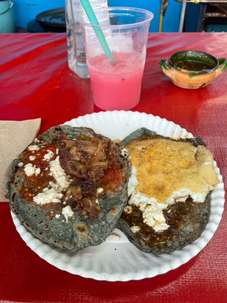 Two tasty memelas made of blue born with cheese, egg, and pork on top at the Central Abastos Market in Oaxaca City.