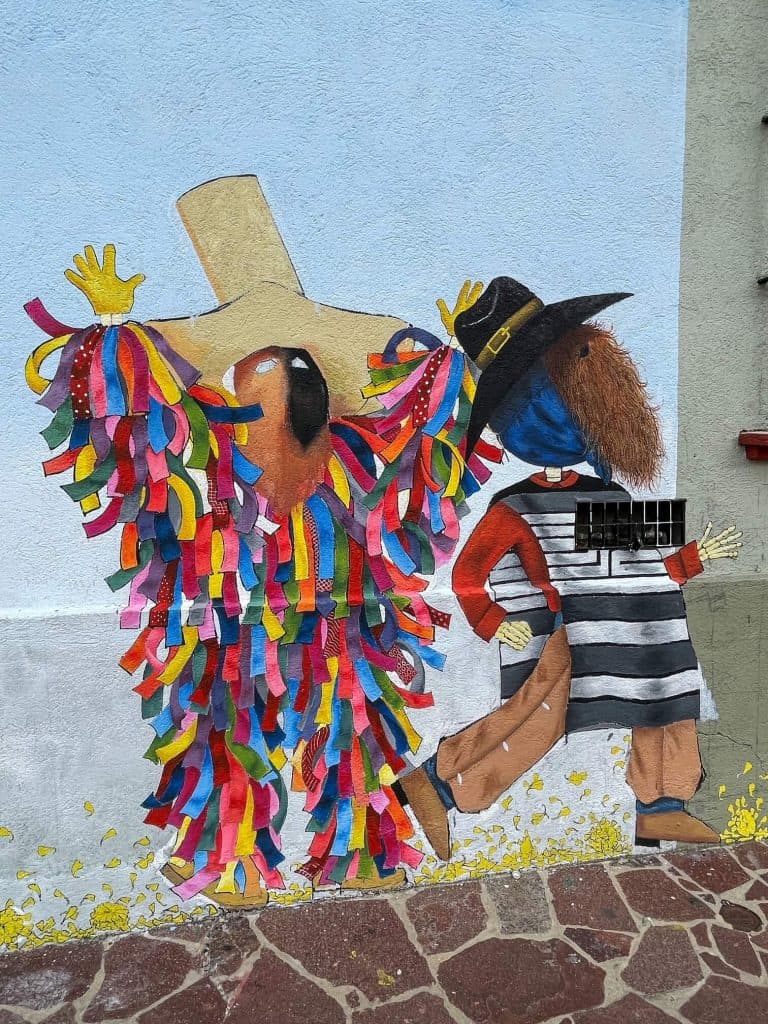 Local characters from Oaxaca are painted on a wall in bright colors in Xochimilco neighborhood of Oaxaca.