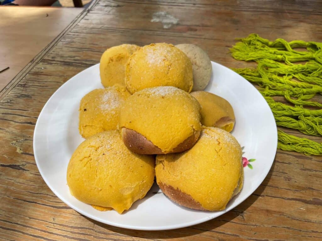 A plate full of sweet bread pastries known as pan that are an orange yellow color and a delicious Oaxacan food.