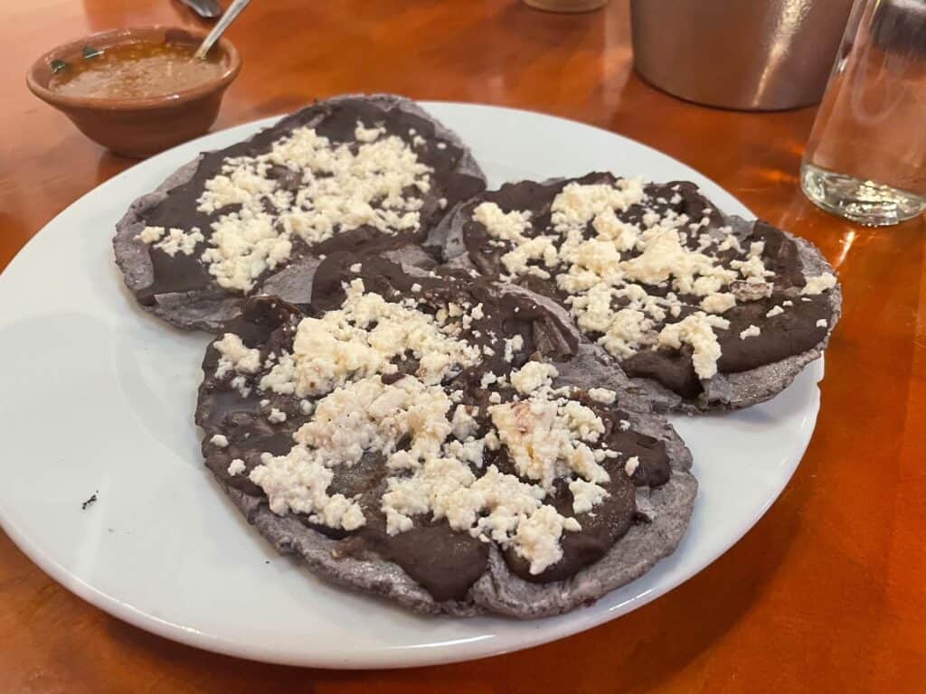 A plate of three memelas topped with beans and Oaxacan cheese at a restaurant in Oaxaca, Mexico.