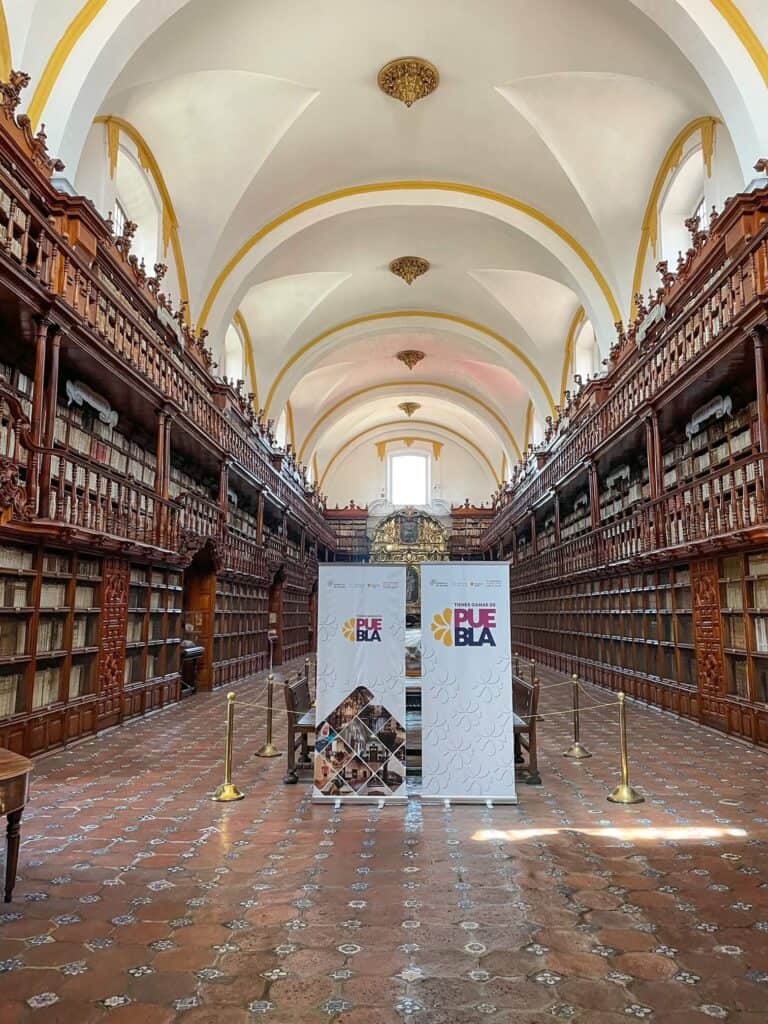 View of the entire Biblioteca Palafoxiana from the door with its gorgeous two levels of wooden bookecases, ancient books, and tiled floor in Puebla, Mexico.