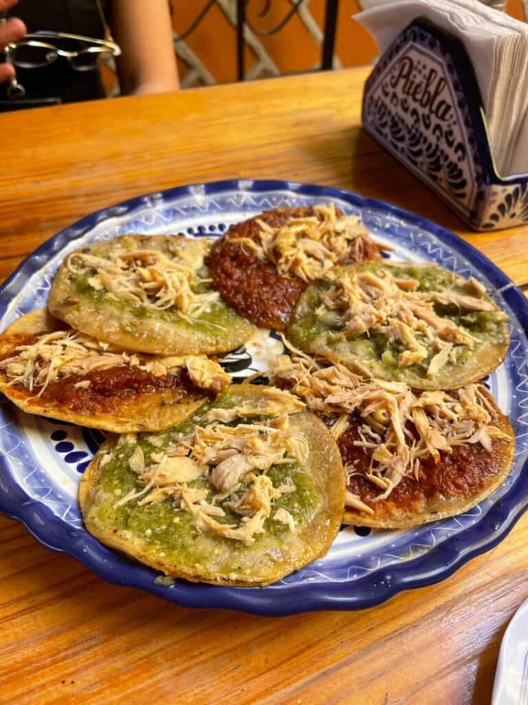 A plate with 6 small chalupas topped with pork and either a red or green sauce.