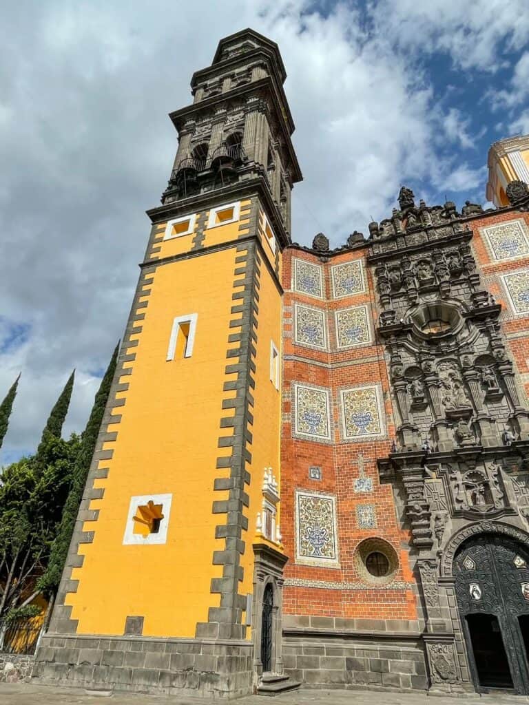 A close-up on the yellow and stone tower section of the church with striking color and craftsmanship.