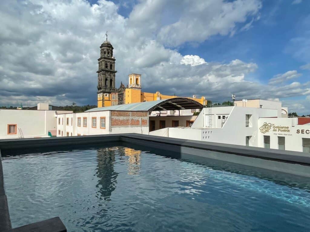 View of a church tower with its reflection in the pool at Hotel La Purifcadora in Puebla.
