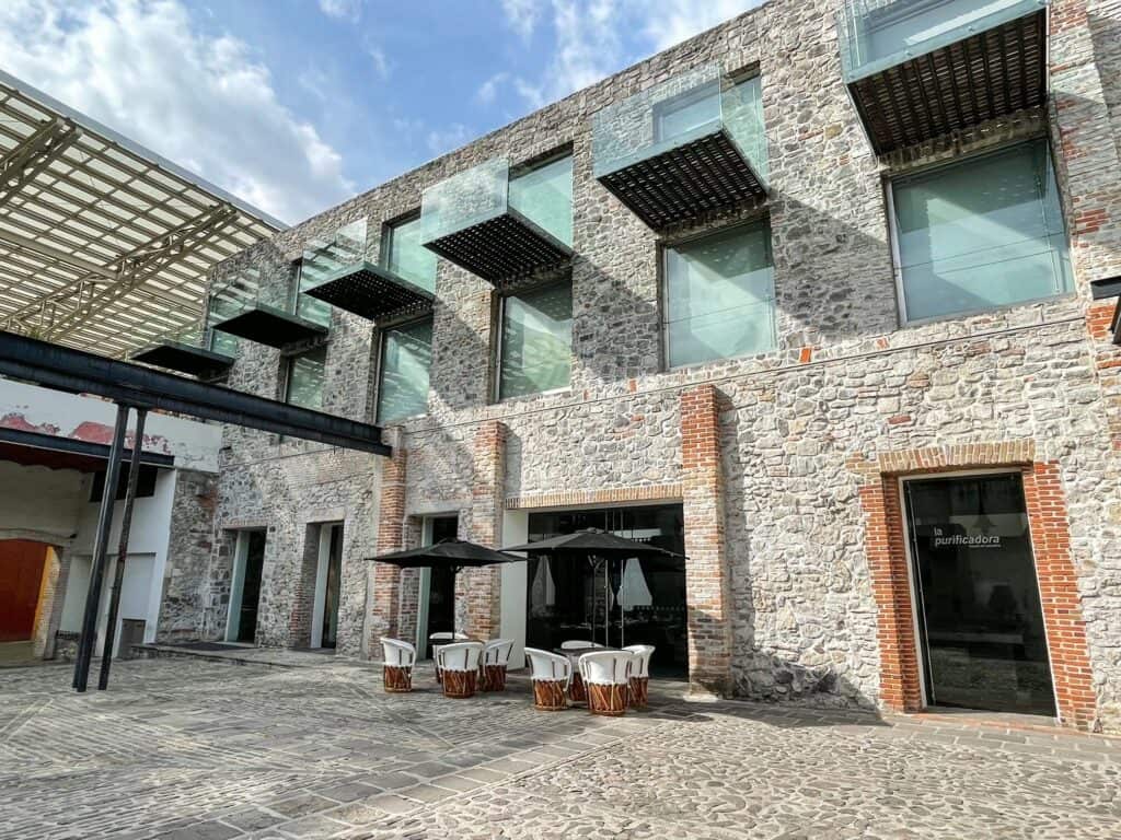 The exterior view of Hotel La Purificadora with part modern such as the glass balconies with the historic ruins featured in the first floor.