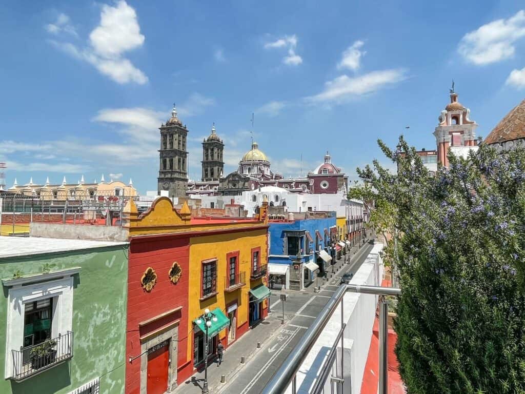 Standing on the edge of the rooftop cafe looking down at the bright colored buildings and with the Catedral de Puebla towers in the distance.