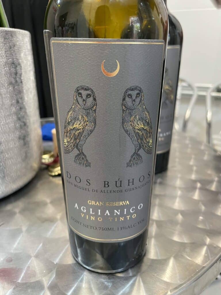 A bottle or red wine with a silver colored label with two owls on it from Dos Buhos organic winery near San Miguel de Allende.