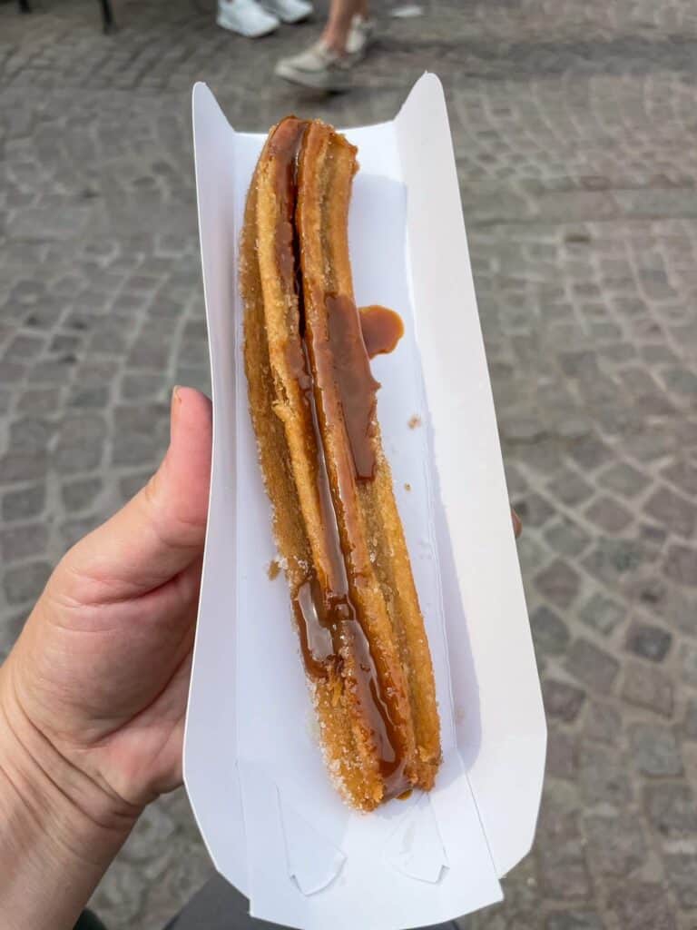 Holding a churro that has been stuffed with a caramel like sauce and enjoying it at the park across from San Agustin cafe in San Miguel de Allende.