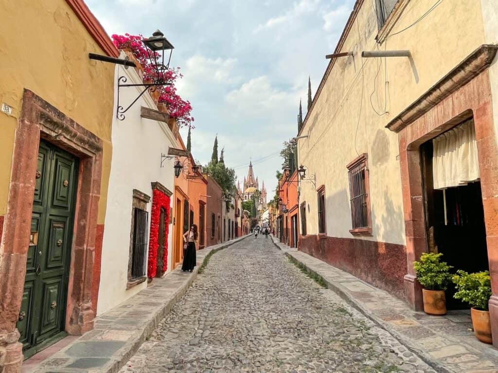 Walking along one of the most picturesque cobblestoned streets with the church towers in the distance, just one of the best things to do in San Miguel de Allende, Mexico.