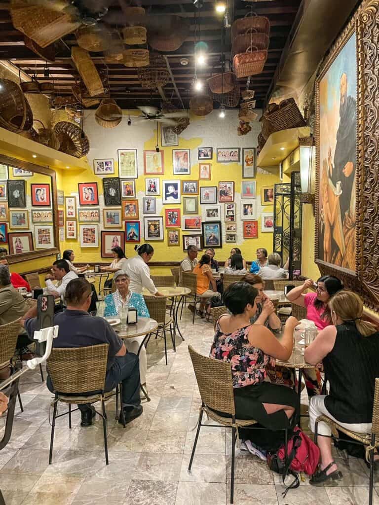 Inside view of the cute and cozy San Agustin cafe with its yellow walls covered in photos and artwork in San Miguel de Allende historic center.