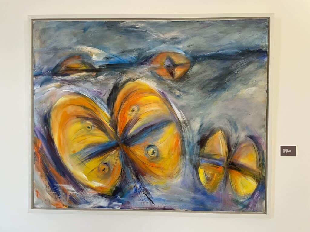 A beautiful painting of abstract butterflies in shades of yellow with a background of blues, white, and grey.