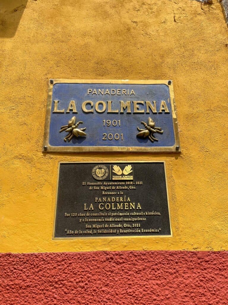 The blue sign for La Colmena on the outside of the building with bees on it and 1901, the year it opened.