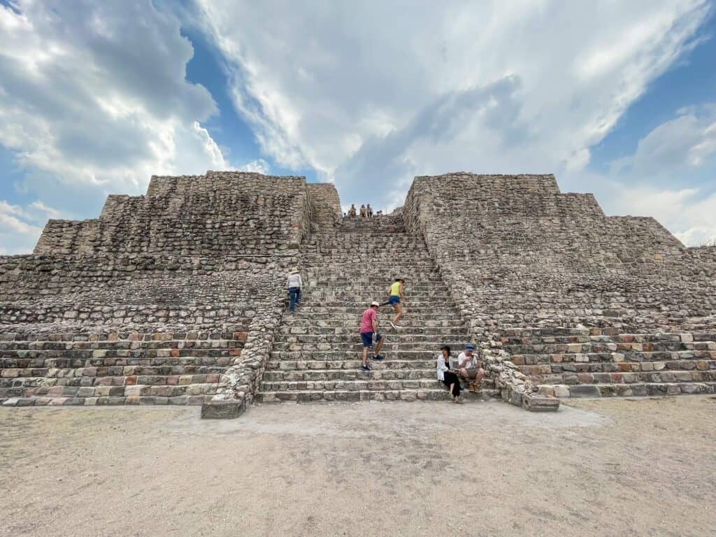 Standing in front of the ancient pyramid at Canada de la Virgen watching people climb up the steep steps.