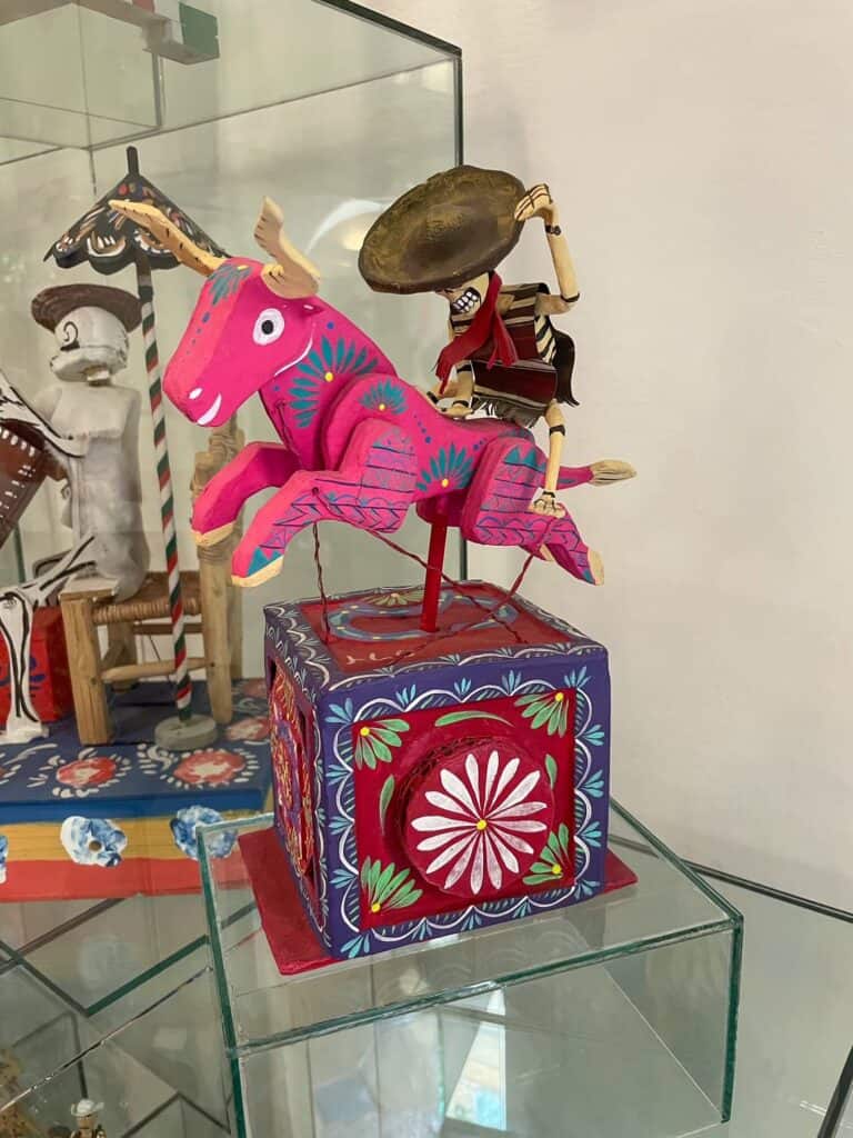 A small red box with a pink steer and a skeleton riding it, just one of the many colorful and cool toys at the Toy Museum in San Miguel de Allende.