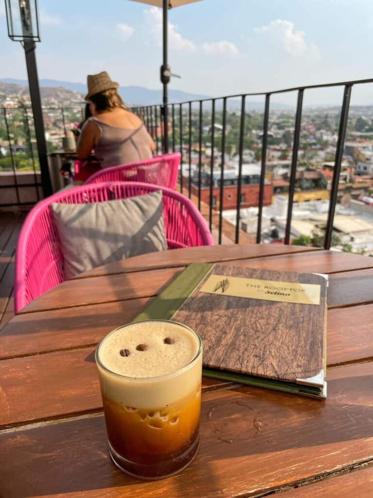 Sipping on a tasty Carajillo coffee cocktail looking out over the city with pink chairs and umbrellas at Selina Rooftop Bar in San Miguel de Allende.