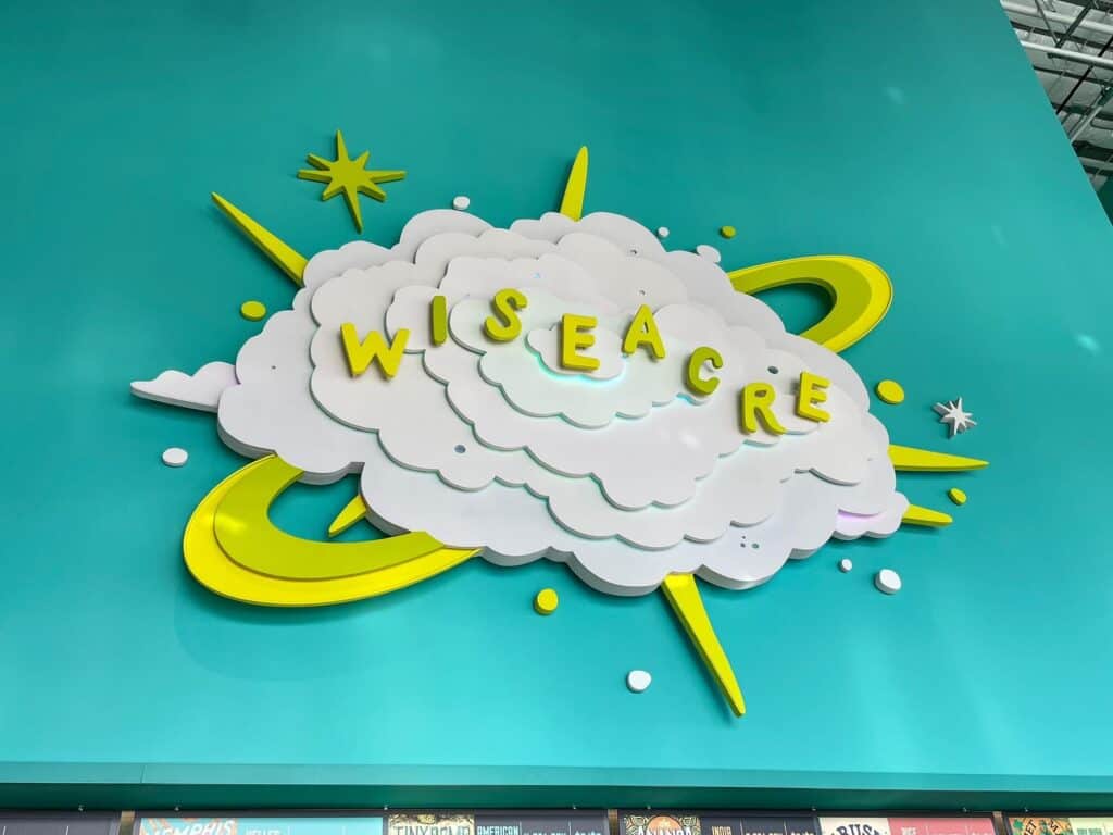 A close up of the Wiseacre beer logo and sign of a white cloud with yellow stars and orbits around it with a pale turquoise background at the Wiseacre Brewery in Memphis.